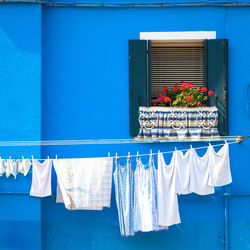 Clothes drying on clothesline hanging against blue building