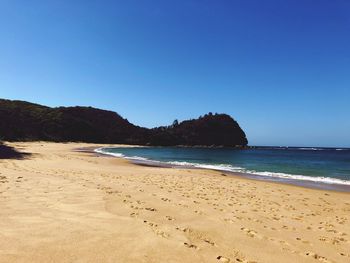 Scenic view of beach against clear blue sky