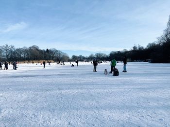 People on snow field against sky