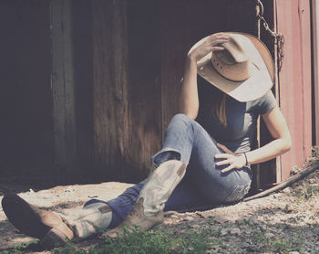 Woman in hat sitting on field