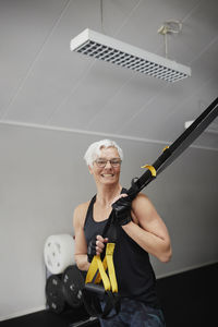 Smiling senior woman standing in gym and looking at camera
