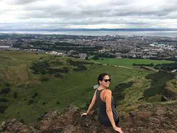 High angle view of woman sitting on cliff at arthur seat