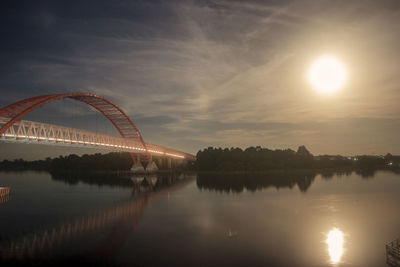 Arch bridge over river against sky during sunset