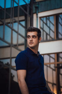 Portrait of young man standing against railing