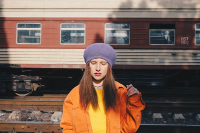 Beautiful young woman standing against train at railroad station