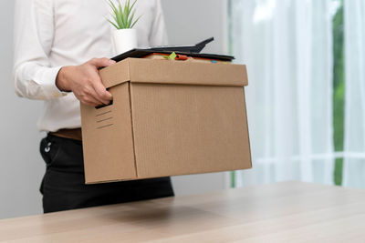 Midsection of man holding paper while standing on table