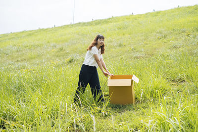 Full length of woman holding umbrella in field