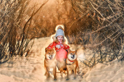 Cute smiling girl sitting on sled by dogs in snow covered forest