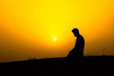 Silhouette man standing against orange sky during sunset