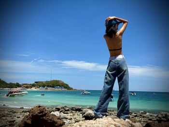 Rear view of man standing at beach against sky
