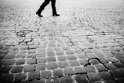 Low section of man walking on cobblestone