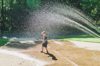 Boy playing in sprinkler water