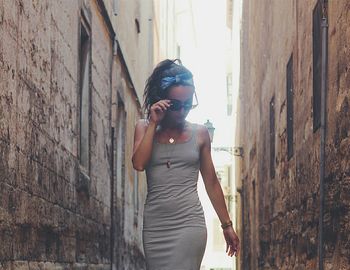 Beautiful woman with sunglasses while standing in alley