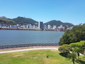 Scenic view of sea and buildings against clear blue sky