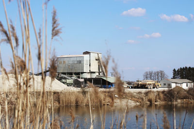 Abandoned boats on field by lake against sky