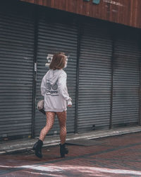 Rear view of woman standing against wall