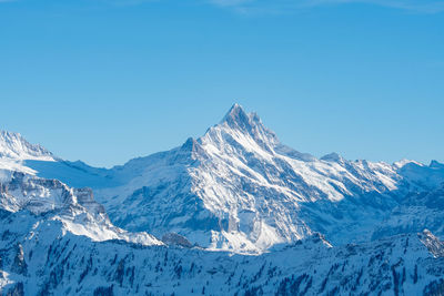 Scenic view of snowcapped mountains against clear blue sky