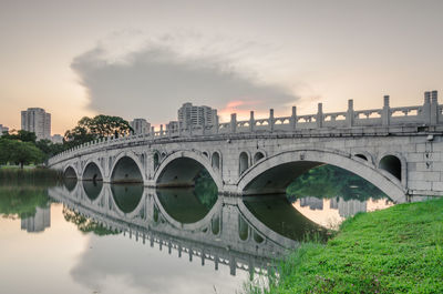 Bridge over river in city against sky