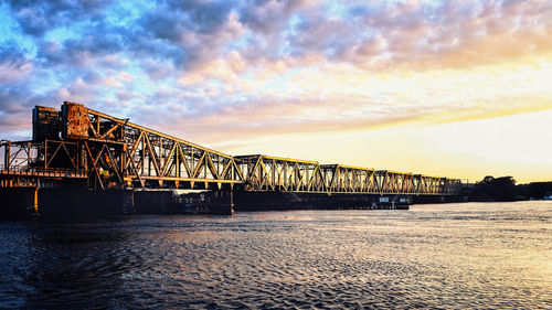 Bridge over river against sky during sunset