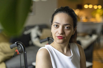 Portrait of young woman sitting on wheelchair at home