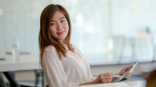 Portrait of smiling woman holding digital tablet