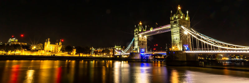 Illuminated bridge over river at night