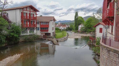 Buildings by river against sky