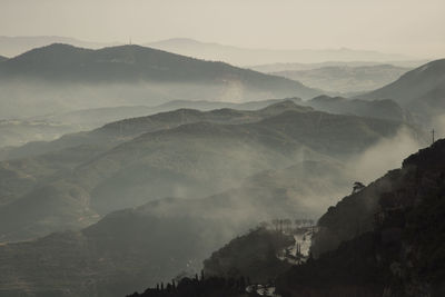 Silouettes of mountains covered by fog in view from montserrat mountain in catalonia