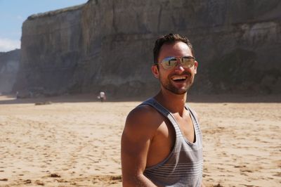 Portrait of young man standing on sand at beach