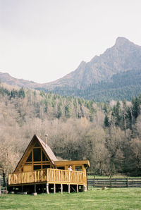 Built structure by calm lake against mountain range