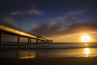 Bridge over sea against sky during sunset