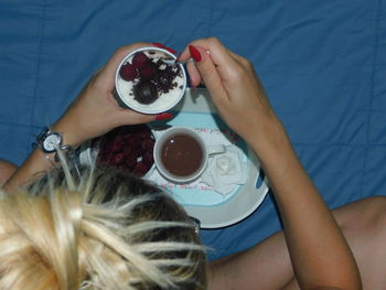 High angle view of woman holding coffee cup on table