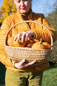 Middle-aged blond caucasian woman in a yellow demi-season jacket with pumpkins