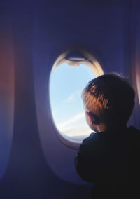 Side view of woman looking through window