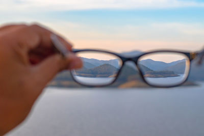 Close-up of eyeglasses at beach against sky