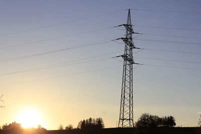 Low angle view of silhouette electricity pylon against sky during sunset