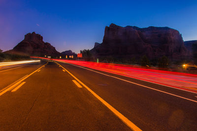 Light trails on road against sky at dusk