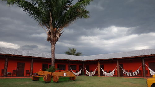 View of palm trees and building against cloudy sky