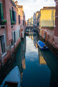 Canal amidst buildings in city against sky