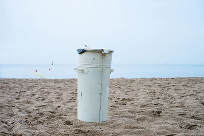 Garbage bin at beach against clear sky