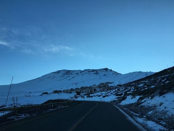 Road by mountains against clear blue sky