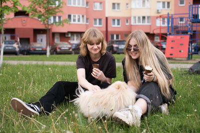 Two funny girls are eating ice cream and playing with a pomeranian dog. holidays