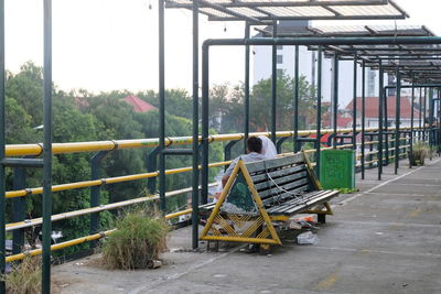 Rear view of man sitting on railing