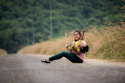 Full length of woman sitting on road