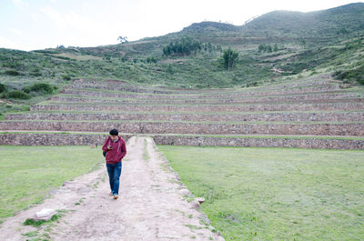 Full length rear view of man walking on landscape