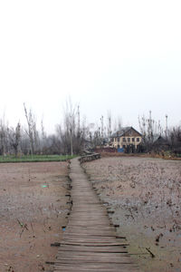 Dirt road amidst buildings against clear sky