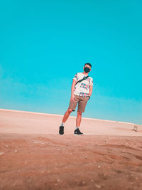 Full length of man standing on land against clear blue sky