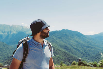 Side view of young man standing against mountain