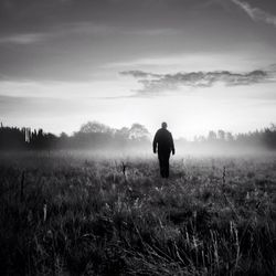 Man walking on grassy field against sky