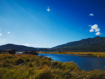 Scenic view of lake and mountains against blue sky